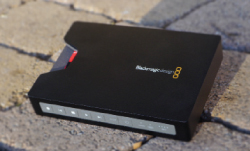 A black Blackmagic Design electronic device resting on a textured stone surface.