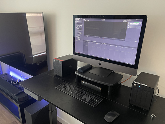 A black desk holding a large computer monitor, keyboard, mouse, and two small computer towers.