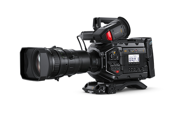 A professional black video camera with a large zoom lens mounted on a tripod base against a white background.