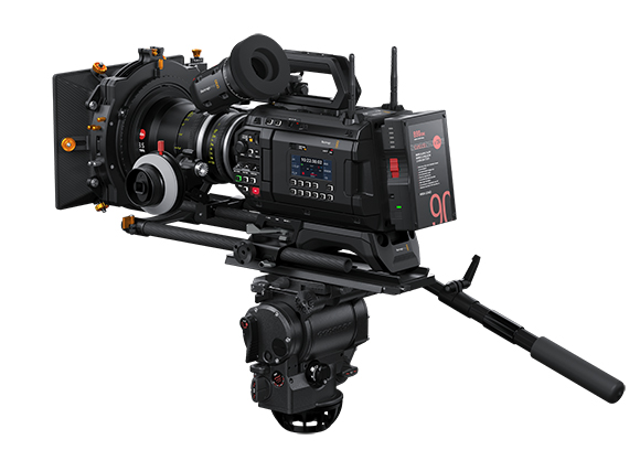 A high-end professional cinema camera equipped with a large lens and monitor, mounted on a fluid tripod head.