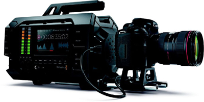 A professional black digital cinema camera with a large lens and a side-mounted display screen.
