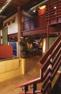 Interior view of a multi-level building with wooden railings, a mezzanine, and a staircase.