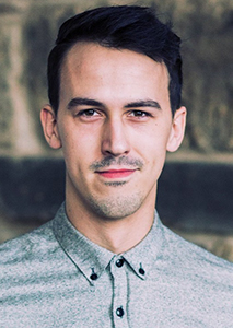 A man with short dark hair and a light mustache looking directly at the camera.