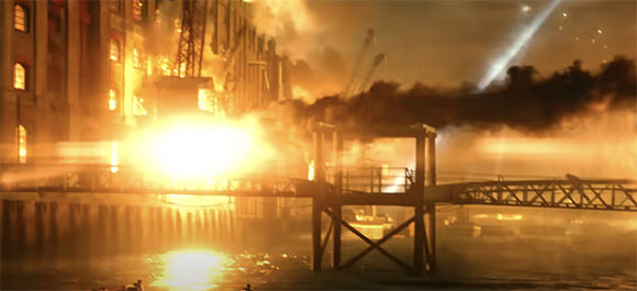 A large building engulfed in bright orange flames next to a pier and water at night.
