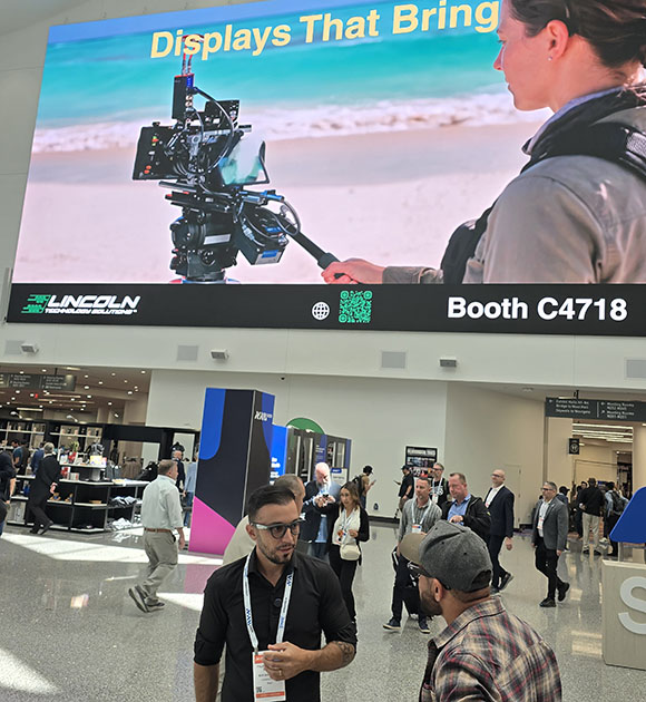 Large screen displays "Displays That Bring" with a camera on a beach, Lincoln Technology Solutions logo, and booth C4718.