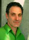 A man with dark curly hair wearing a bright green collared shirt.