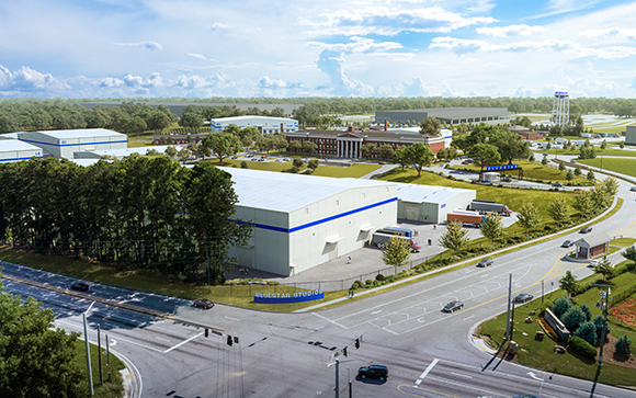 Aerial view of a large industrial complex with white warehouses, green trees, and surrounding roads.