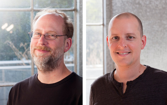 Two headshots of men smiling, one with glasses and a beard, the other bald.