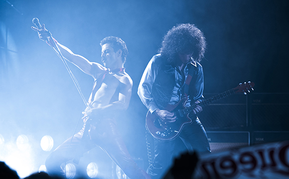 Two musicians performing on a stage with blue spotlights and smoke.