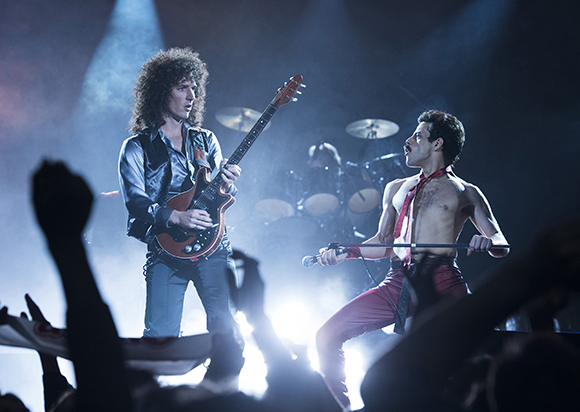 A guitarist and a shirtless vocalist perform on a stage in front of a crowd.