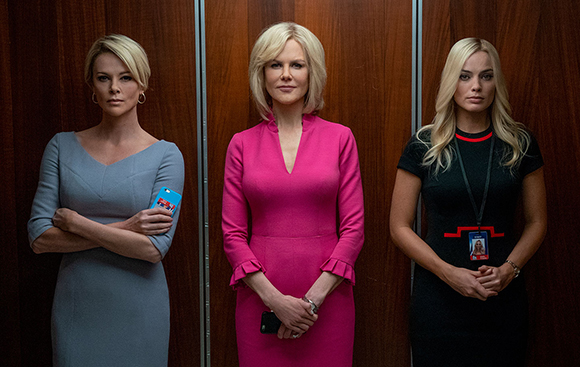 Three women in formal dresses stand side-by-side against a dark wood-paneled wall.
