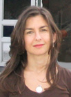 A woman with long brown hair and red lipstick looking toward the camera.