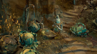 A small, pale creature stands amidst large cabbages and debris in a dim, earthy setting.