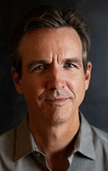 A middle-aged man with short brown hair and a light complexion looking forward.