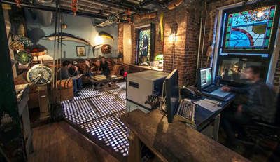 A lounge with a sofa and fish decor next to a workspace with a computer and a person sitting at a desk.