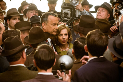 A man and woman stand in a dense crowd of men wearing fedoras and vintage cameras.