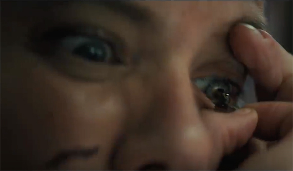 Extreme close-up of a person's eyes looking upward with fingers pulling at the skin near the eye.
