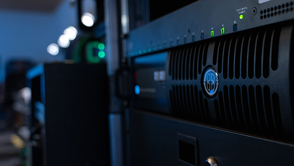 Close-up of black server hardware in a rack with small green indicator lights glowing.