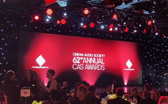 A large red screen displays '62nd Annual CAS Awards' on a stage with bright red and white lights.