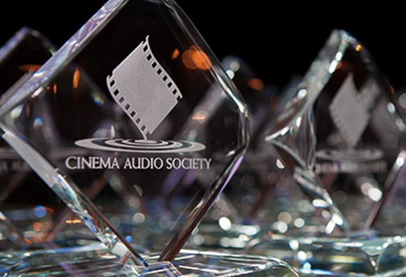 Several diamond-shaped crystal awards with the Cinema Audio Society logo on a reflective surface.