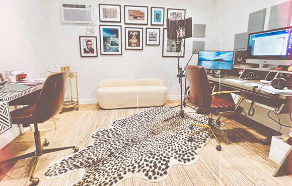 A recording studio featuring a computer workstation, a white sofa, and a large leopard print rug.