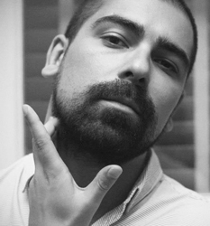 Black and white close-up portrait of a man with a beard resting his hand on his chin.