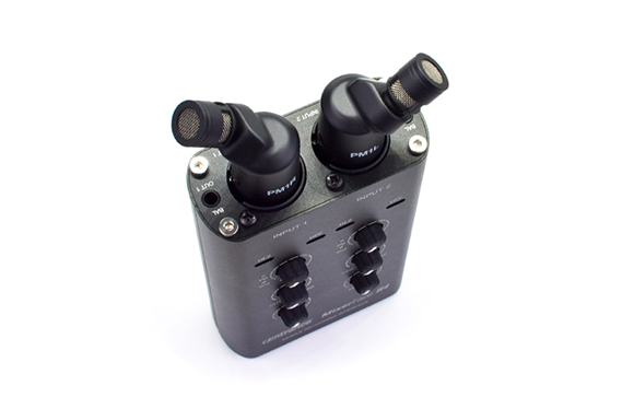 A black MixerFace audio interface with two black in-ear monitors plugged into the top.