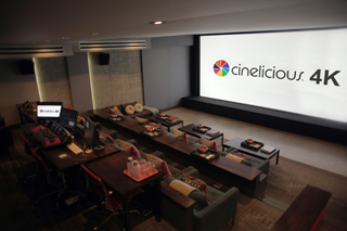A dark screening room featuring a large projection screen displaying the text 'cinelicious 4K'.
