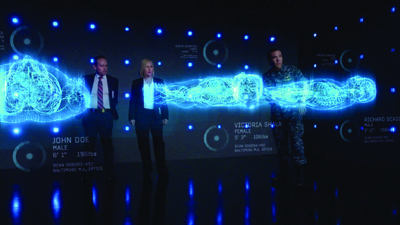 Three people stand in a dark room behind a glowing blue digital brain scan graphic.
