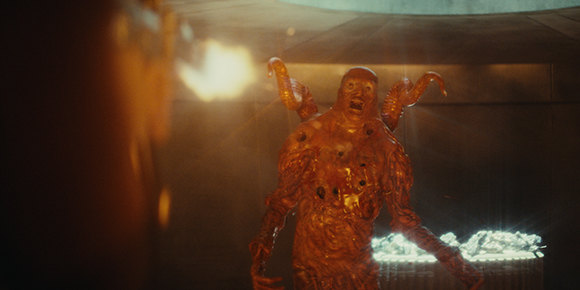 A glowing, orange, humanoid monster with large horns and a distorted face in a dark setting.