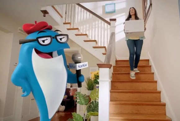 A blue cartoon fish wearing a red beret and glasses holds a microphone in front of a woman walking down stairs.
