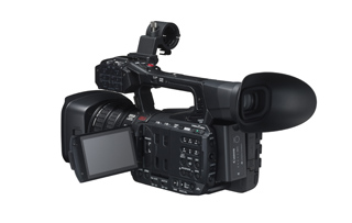 A professional black video camera with a large lens, side screen, and viewfinder.