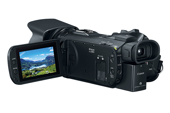 A black Canon digital camcorder with an open LCD screen displaying a landscape of mountains and a lake.