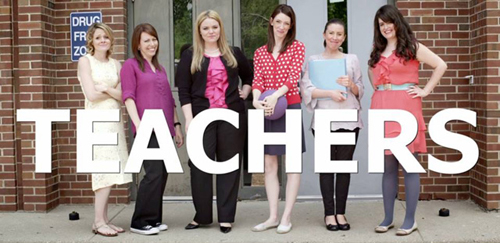 Six women stand in a row in front of a brick building with the word TEACHERS in large white text.
