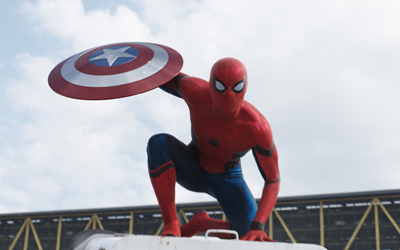 Spider-Man in a red and blue suit crouches while holding Captain America's circular shield against a cloudy sky.