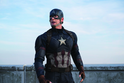 A man in a blue and silver superhero suit with a star on his chest stands against a clear sky.