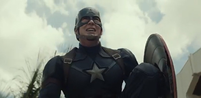 A man in a blue superhero costume and helmet looks up while holding a circular shield.