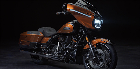 A copper-colored touring motorcycle with a large front fairing and side saddlebags on a dark background.