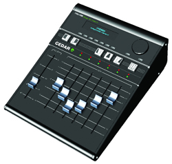 A black Cedar audio mixing console with several vertical faders and small green indicator lights.