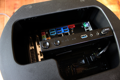 Open computer case revealing the motherboard's rear ports and a black front control panel with buttons and USB.