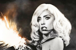 A woman with wavy blonde hair and dark eye makeup looks toward the camera beside bright, glowing sparks.