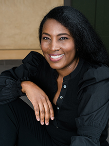 A smiling Black woman with long dark hair wearing a black button-down blouse.