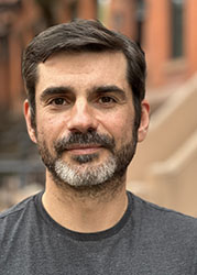 A man with dark hair and a salt-and-pepper beard looking at the camera.