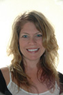 A smiling woman with wavy blonde hair looking toward the camera.