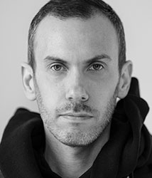 Black and white close-up portrait of a man looking directly at the camera.
