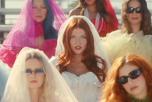 A group of women wearing white and colorful veils and outfits outdoors.