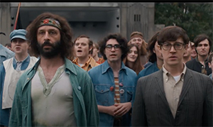 A group of young men and women standing in a crowd, looking forward with various expressions.