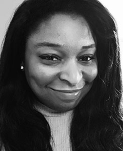 Black and white close-up portrait of a smiling woman with long dark hair.