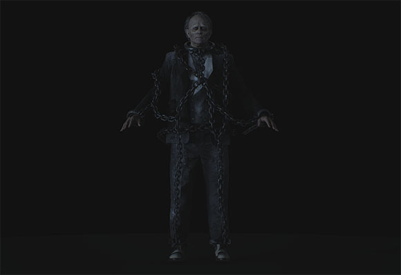 A man in a suit stands against a black background, wrapped in thick metal chains.