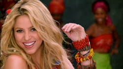 A smiling blonde woman wearing multiple colorful beaded bracelets in a vibrant setting.